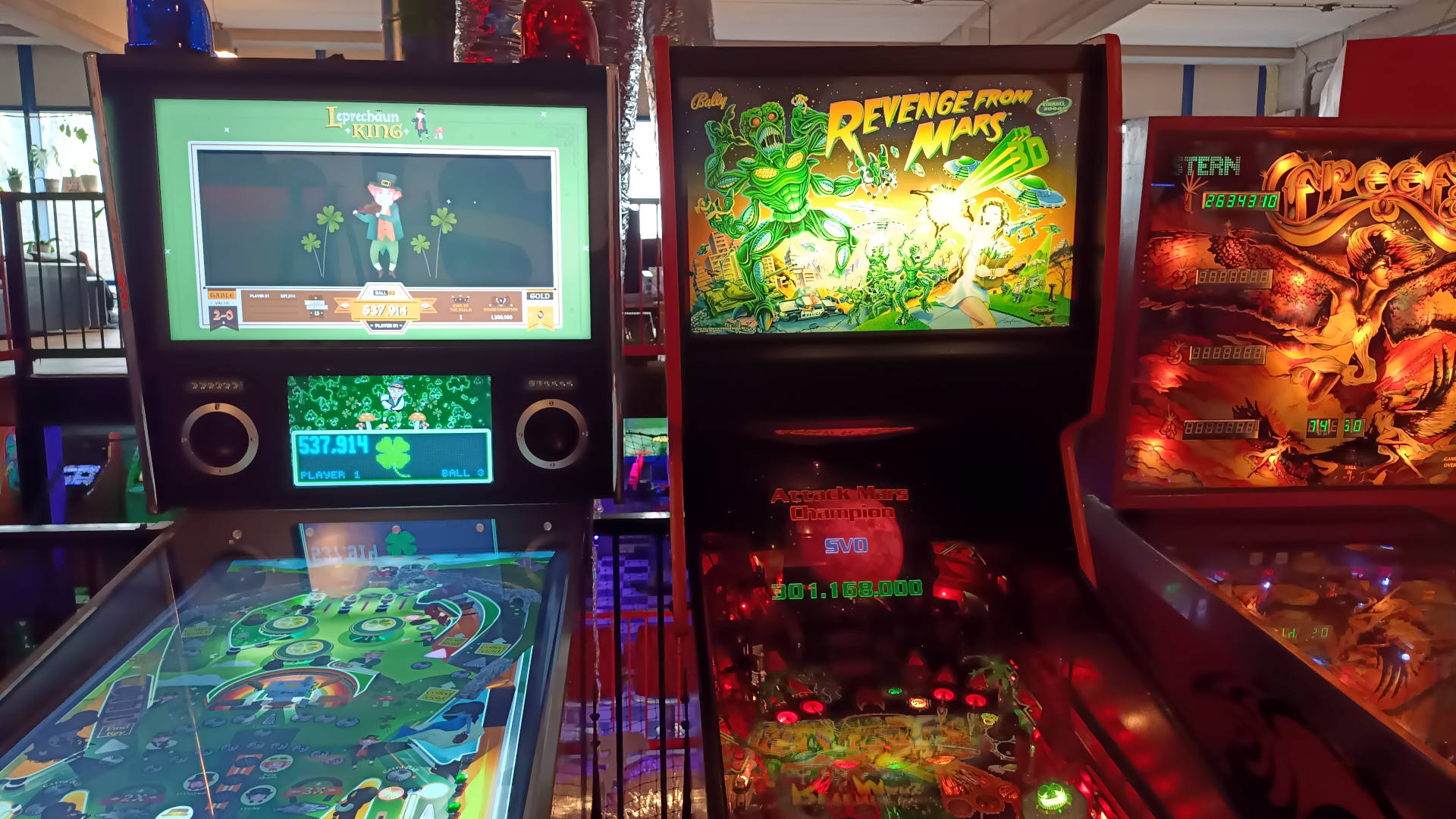 Drie flipperkasten naast elkaar: Leprechaun King, Revenge From Mars en de derde is maar deels zichtbaar