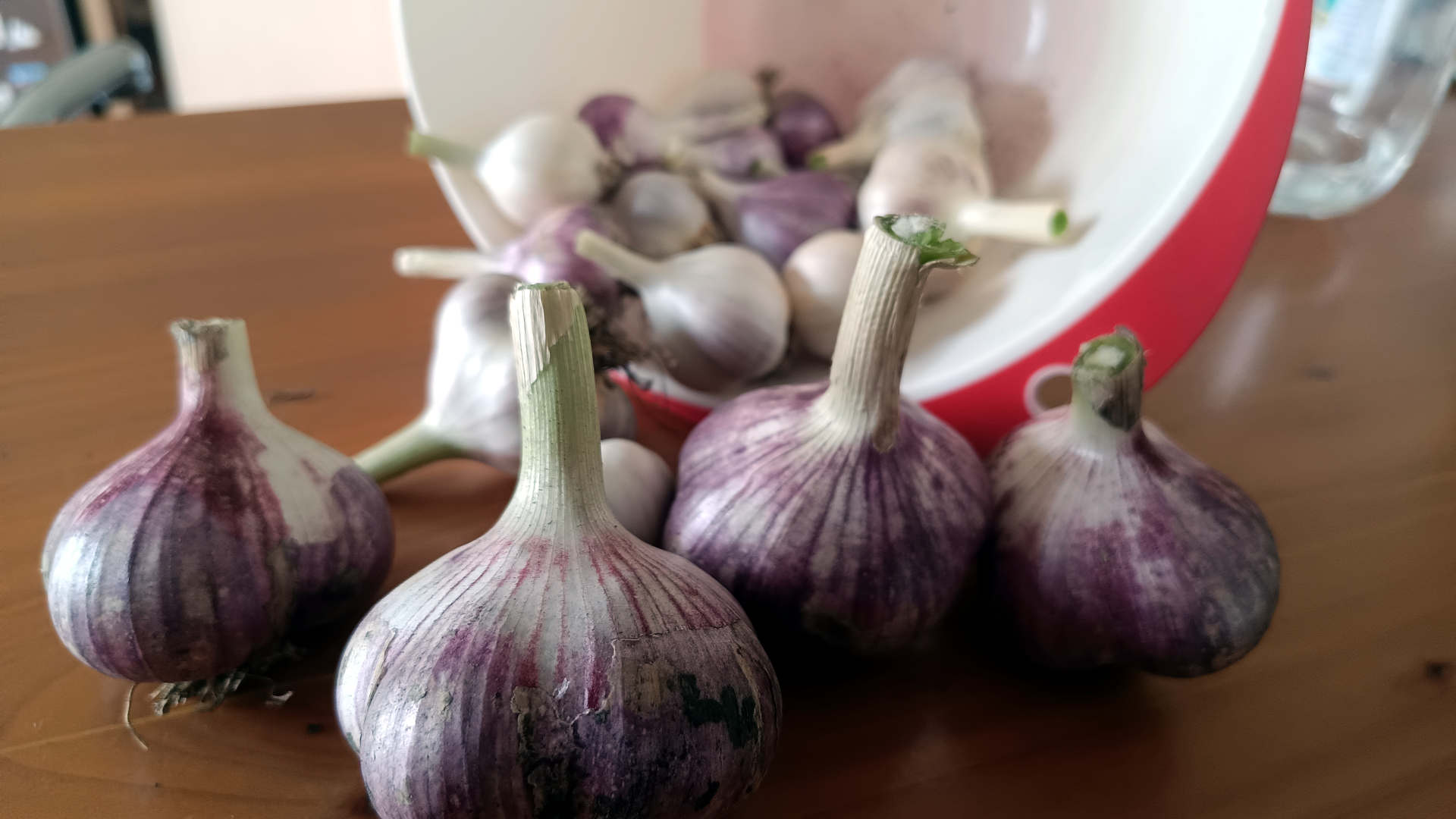 Bolletjes knoflook op een houten ondergrond. Bak op z'n kant met meer knoflook er achter
