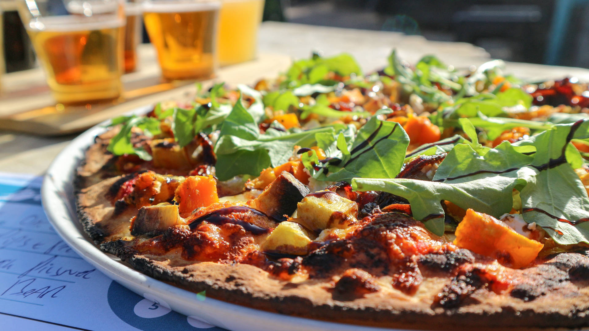 Close-up van versgemaakte pizza bij een brouwerij. Proefplank biertjes op de achtergrond
