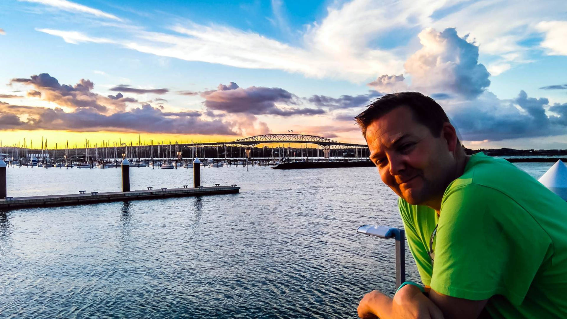 Digital Geek aan de rechterkant, met de Harbour Bridge in Auckland op de achtergrond terwijl de zon onder gaat